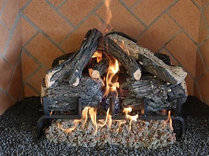 Gas fireplace insert with charred logs, glowing embers, and herringbone brick backing