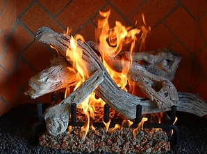 Close-up of weathered grey logs with realistic flames in a brick fireplace