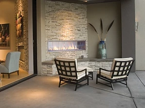 Firegear Kalea Bay outdoor linear fireplace with stacked stone wall at twilight